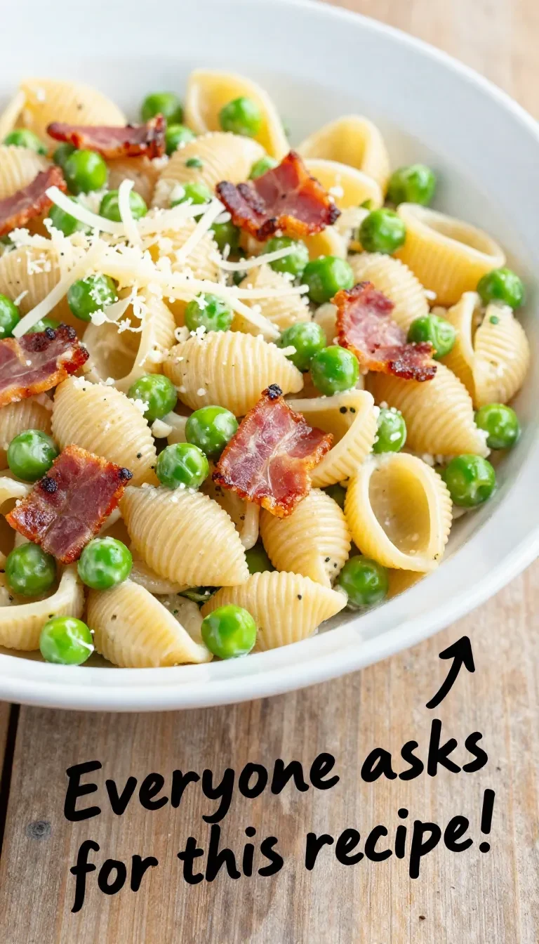 A bowl of creamy pasta salad with fresh vegetables and herbs on a wooden table.